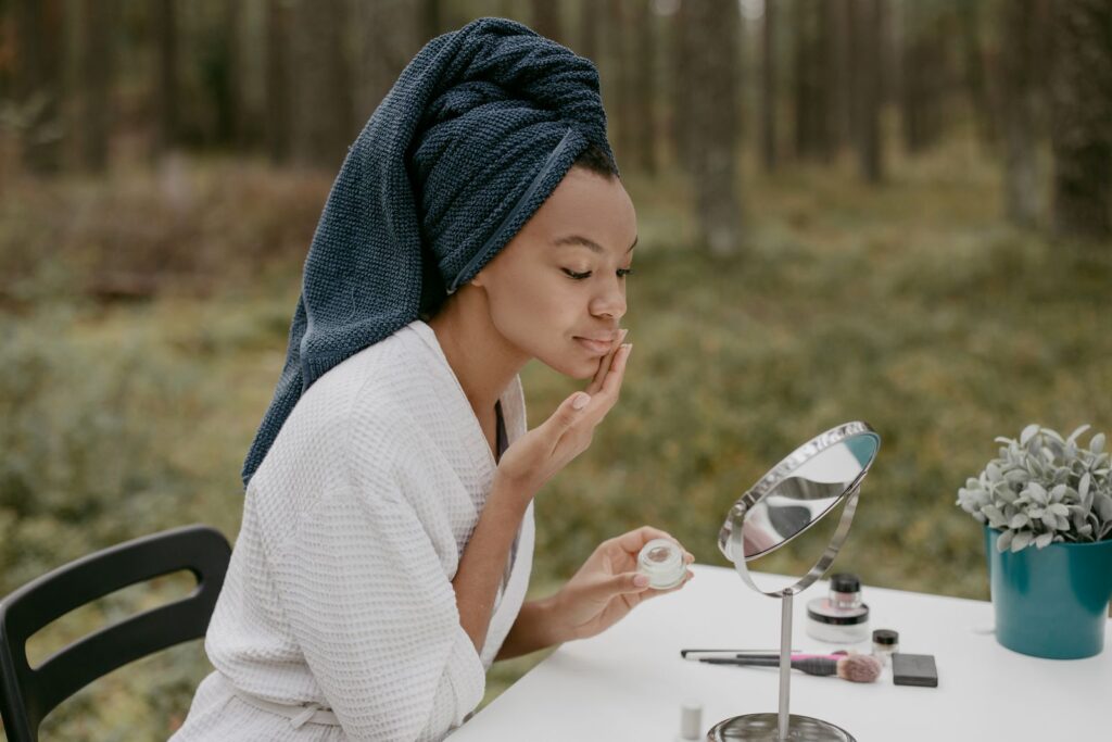 A woman applying face cream in soft outdoor light