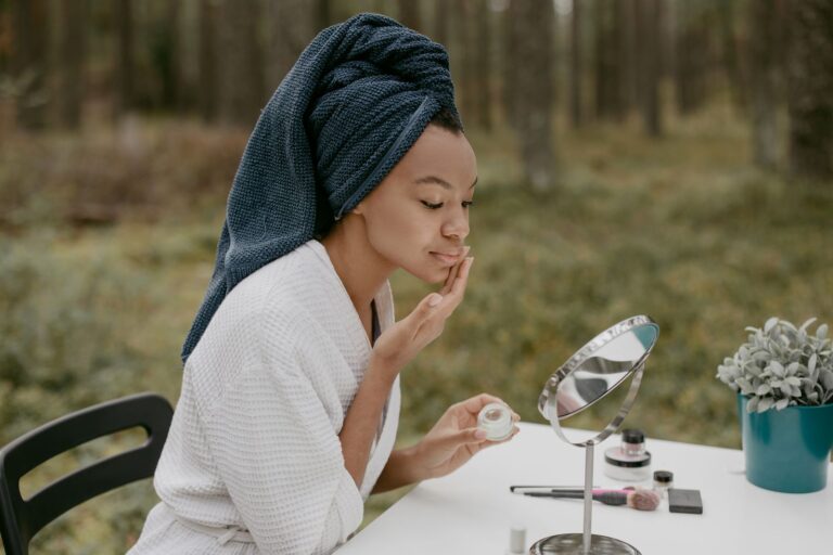 A woman applying face cream in soft outdoor light