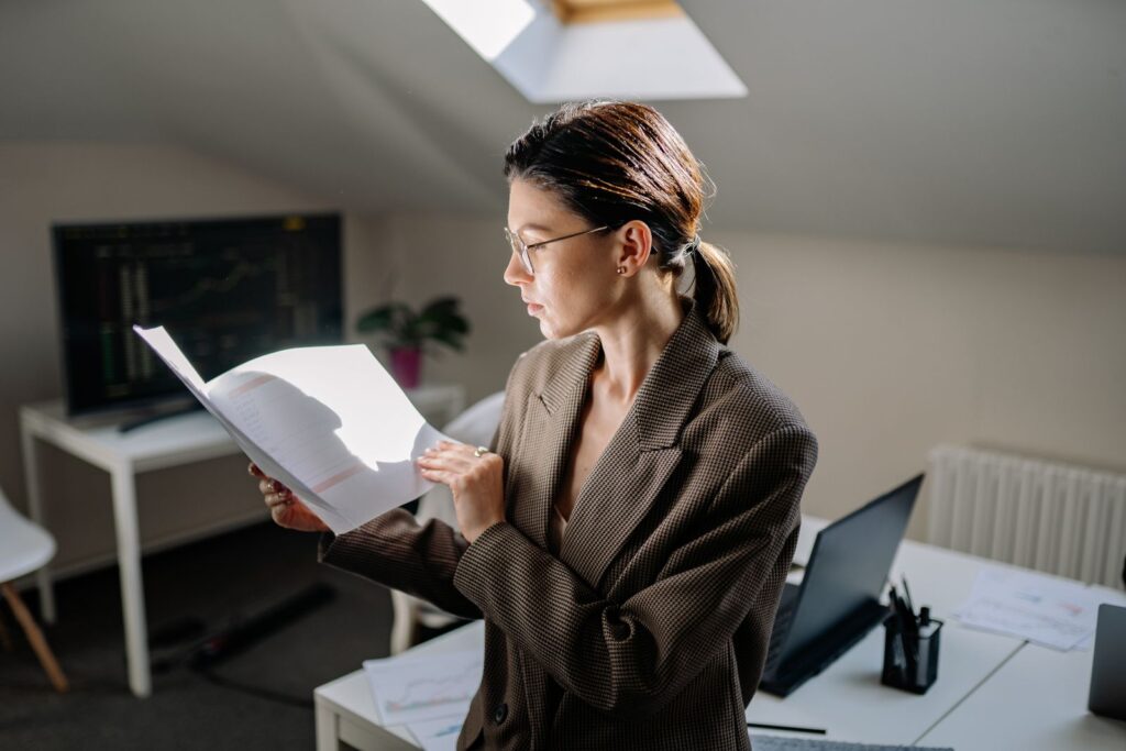 A woman in glasses reviewing printed data at a desk