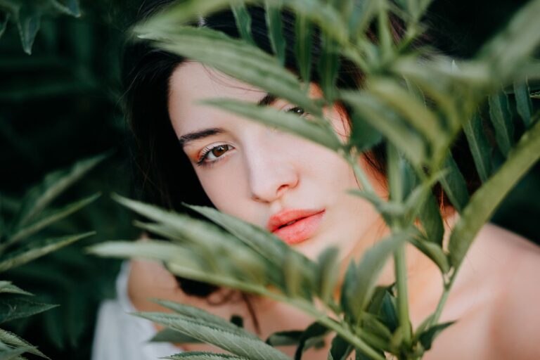 A woman looking through green foliage outdoors