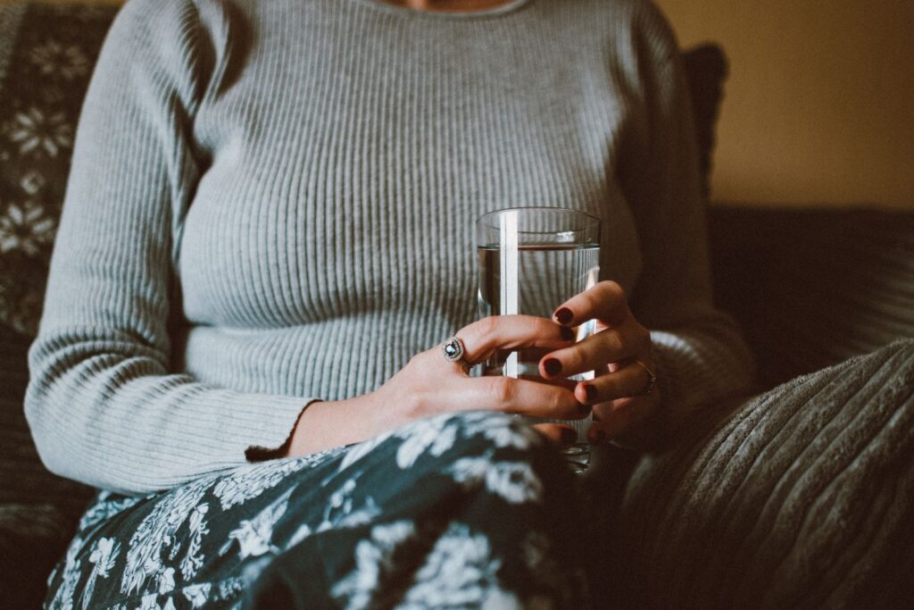 A woman holding a glass of water while sitting indoors