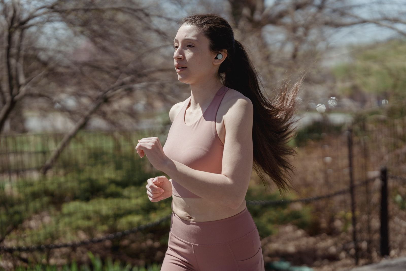 A woman jogging outdoors wearing wireless earbuds