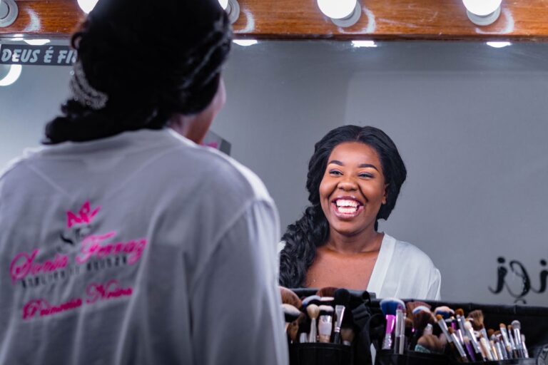 A woman laughing at her reflection in a vanity mirror