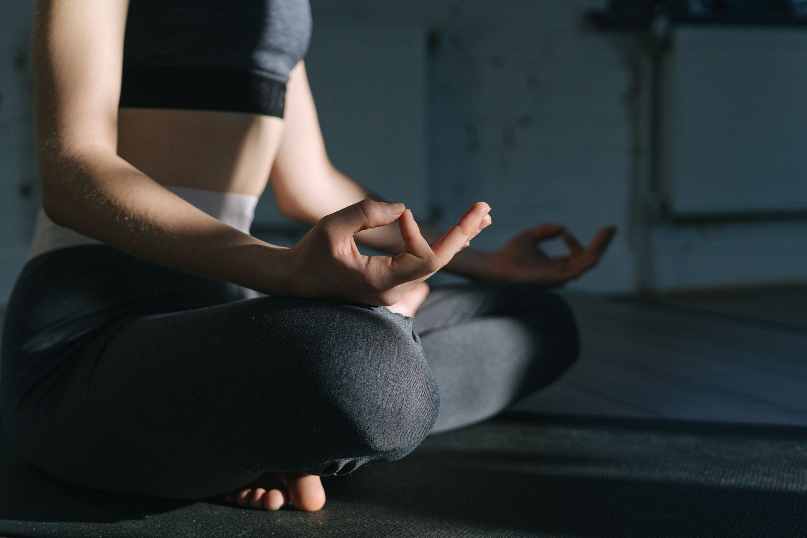 A woman practising mindfulness on a mat indoors