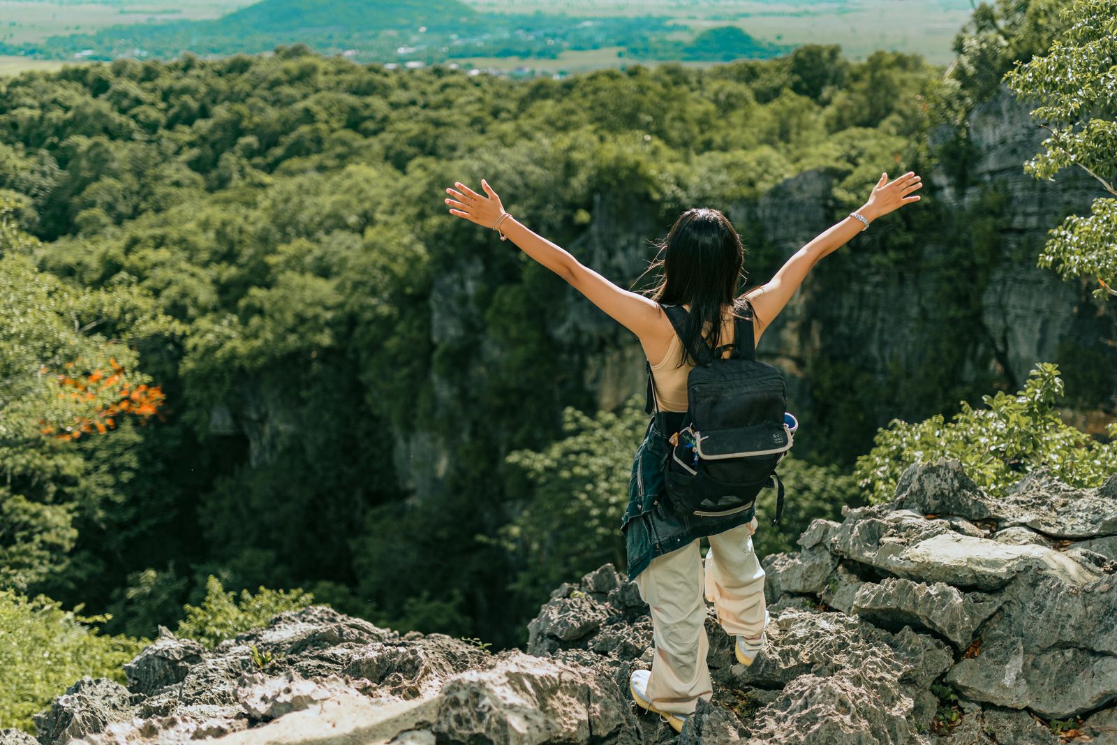 A woman standing with arms raised looking over a mountain view