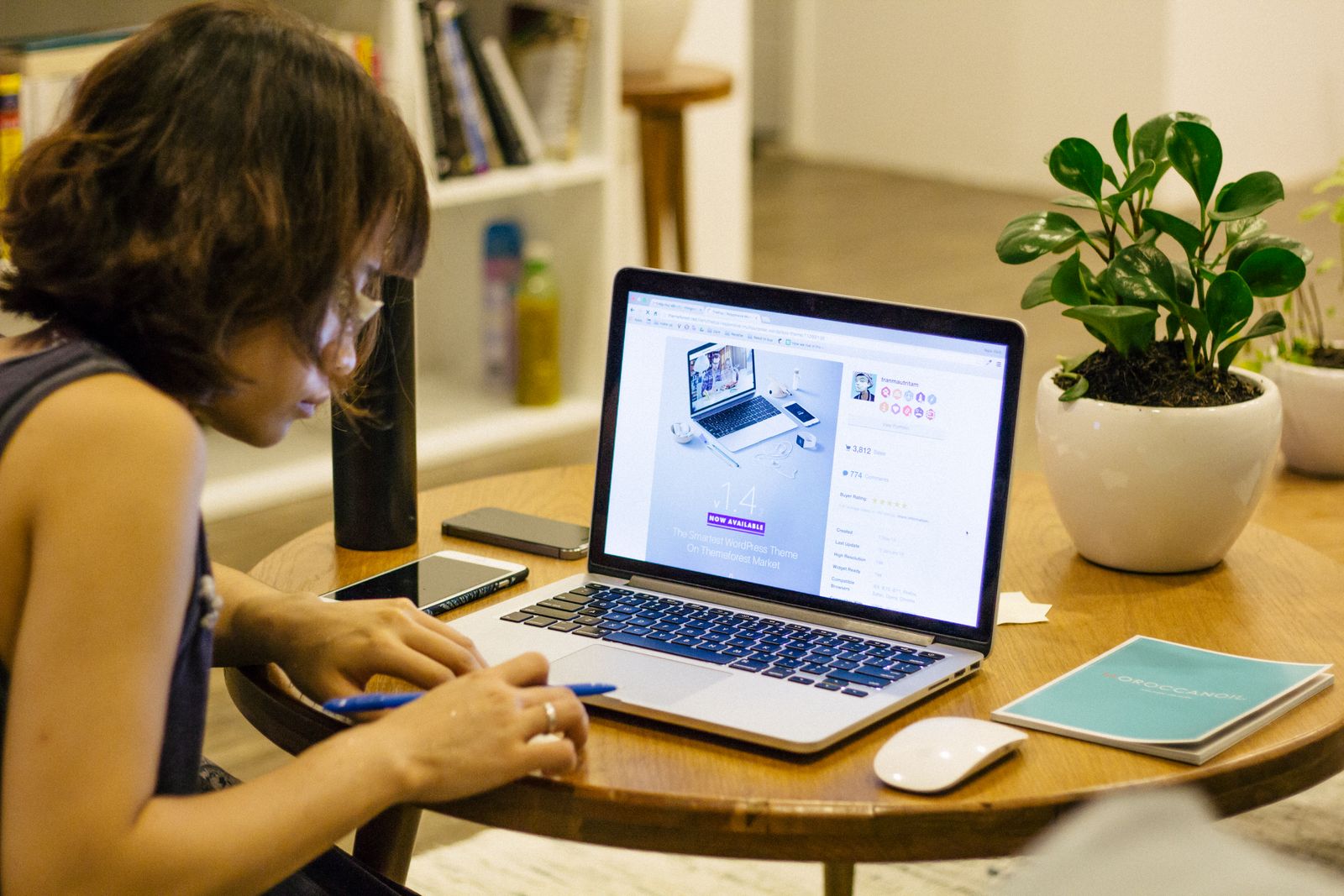 A woman working from home at a desk with a laptop and notebook