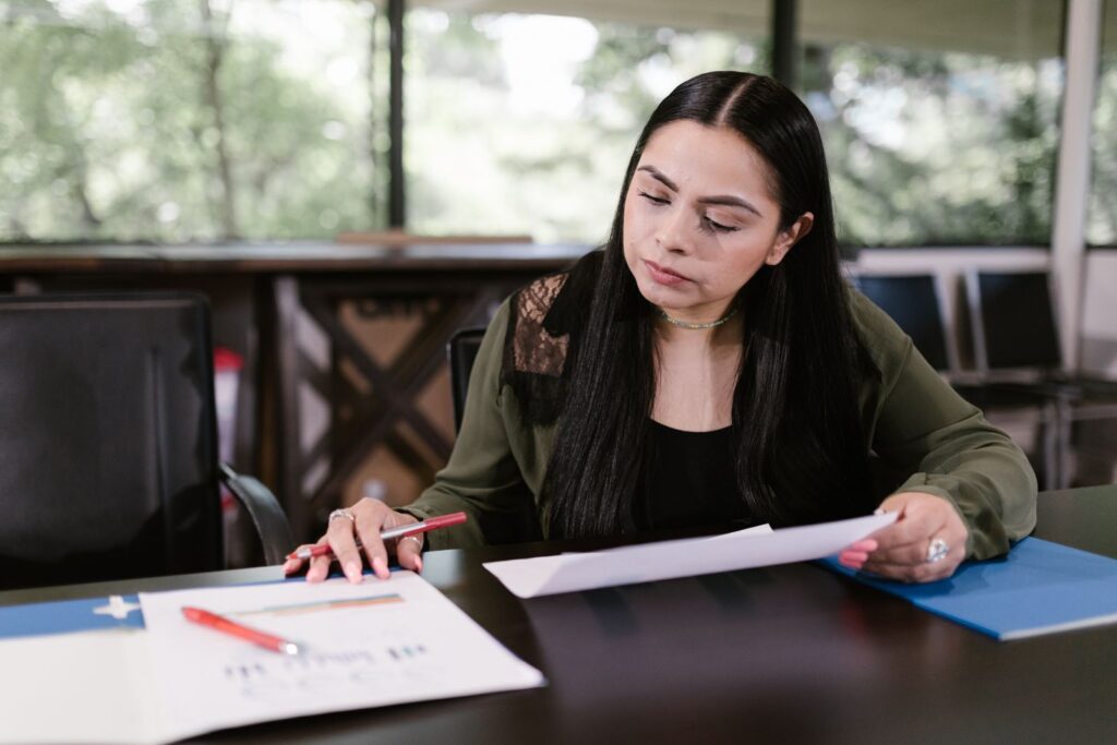 A woman studying documents with close attention at a workspace