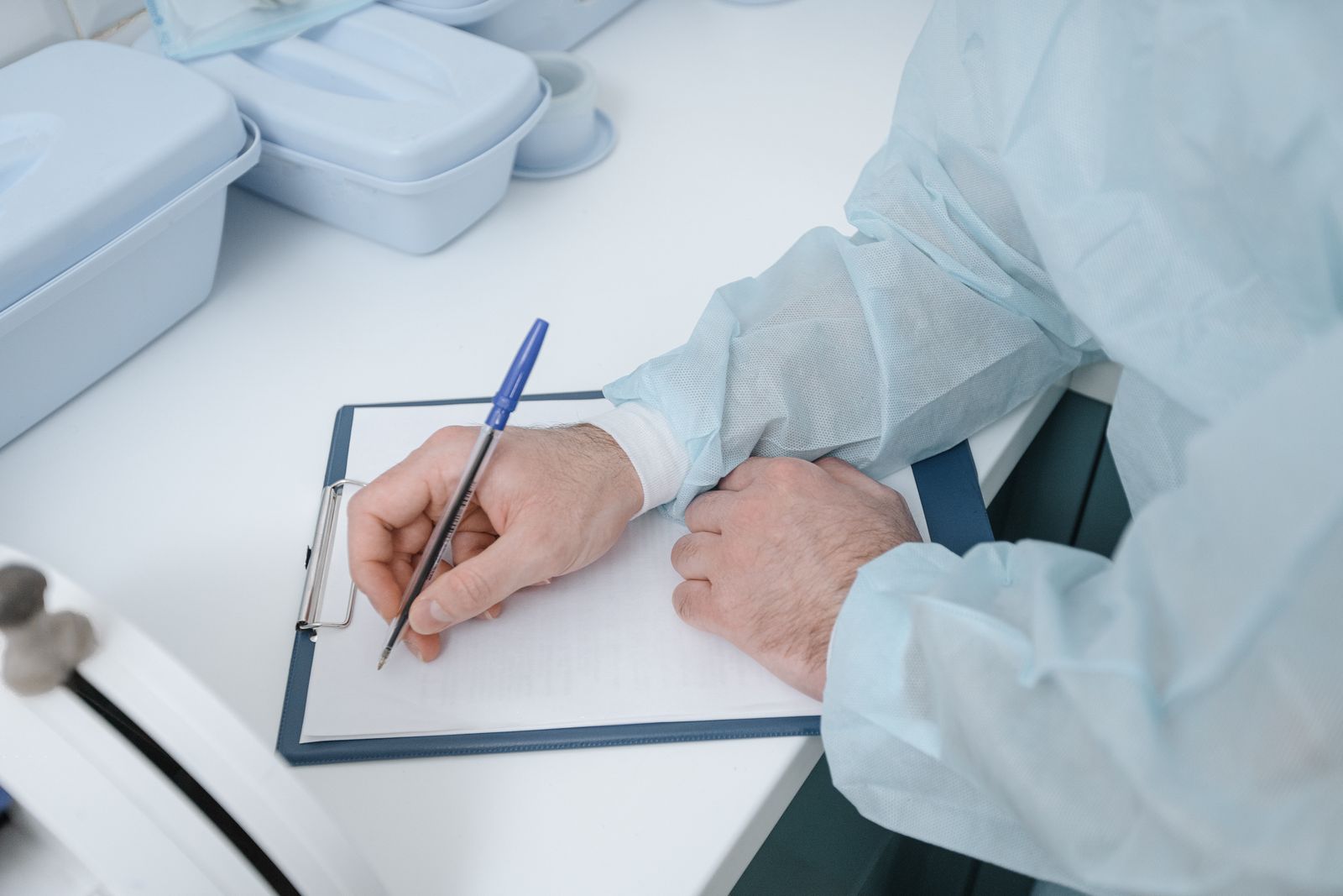 Laboratory professional in protective clothing recording results on a clipboard