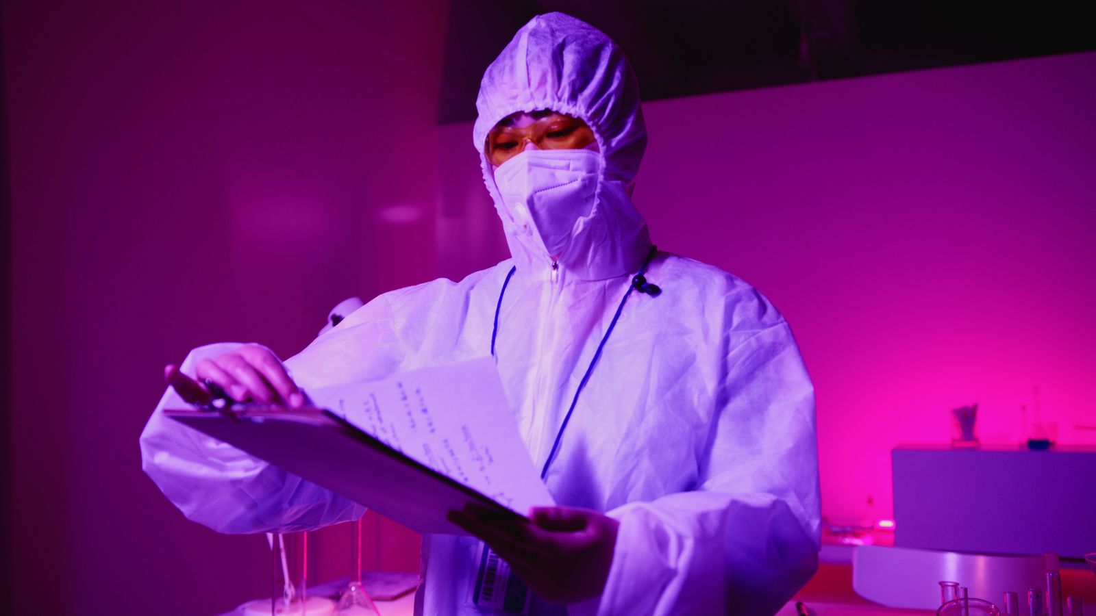 Scientist in protective gear examining research notes in a laboratory
