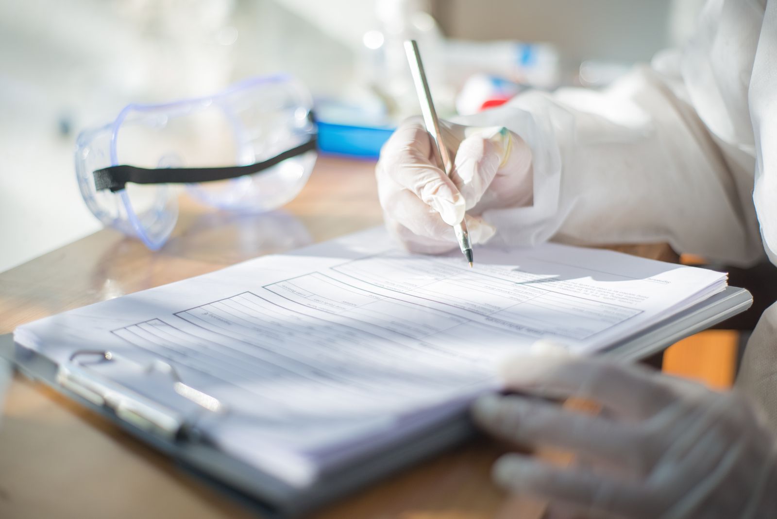 Gloved hands recording results on a document in a laboratory